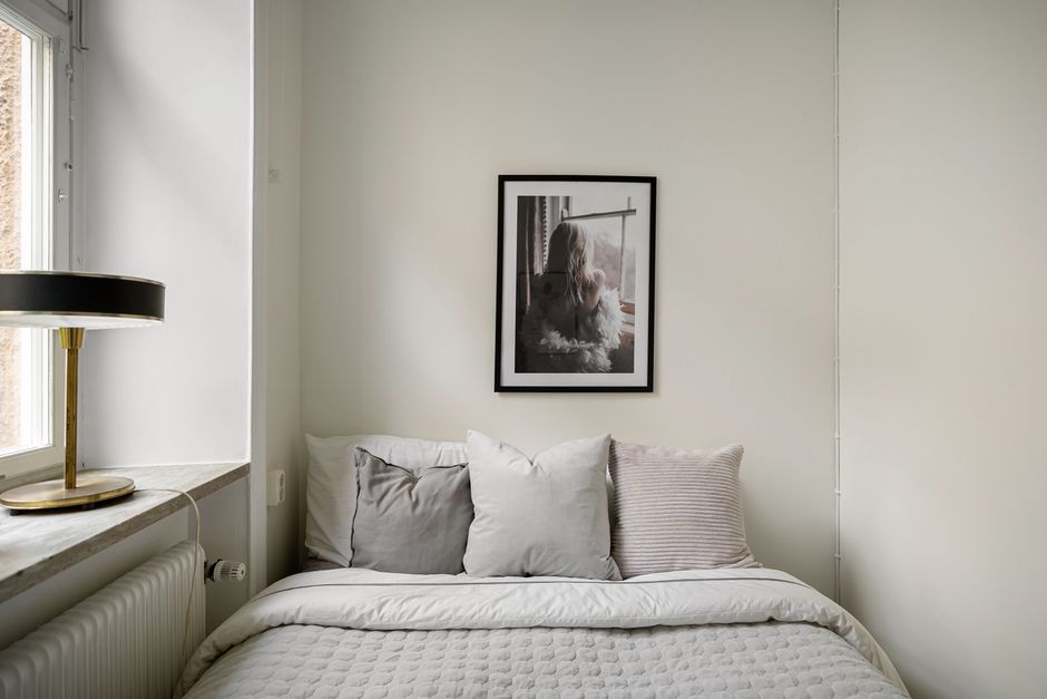 A minimalist bedroom featuring neutral tones, a bed, and an elegant table lamp.