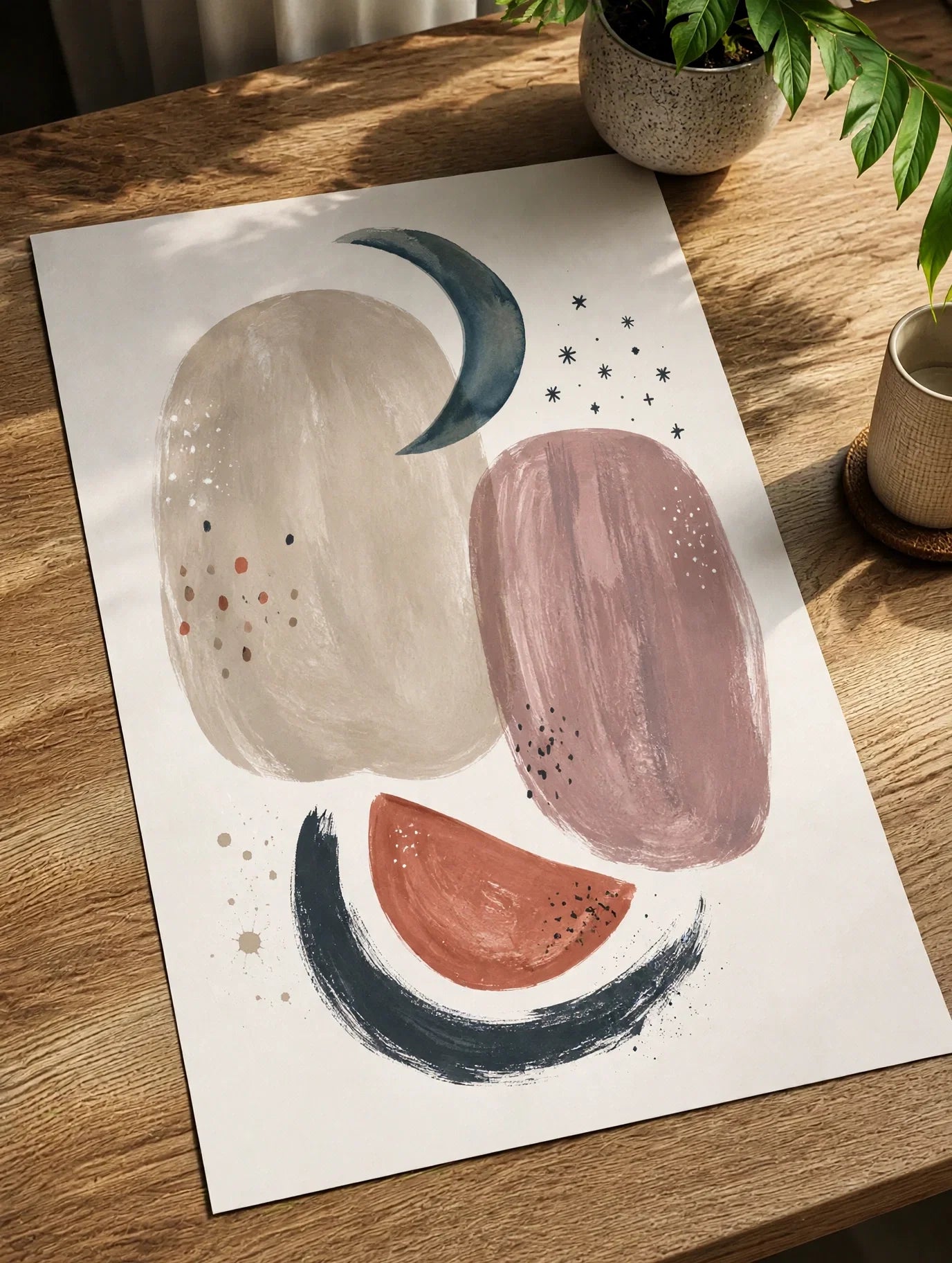 Abstract lunar wall art print on a wooden surface, tilted, with moon and planet shapes.