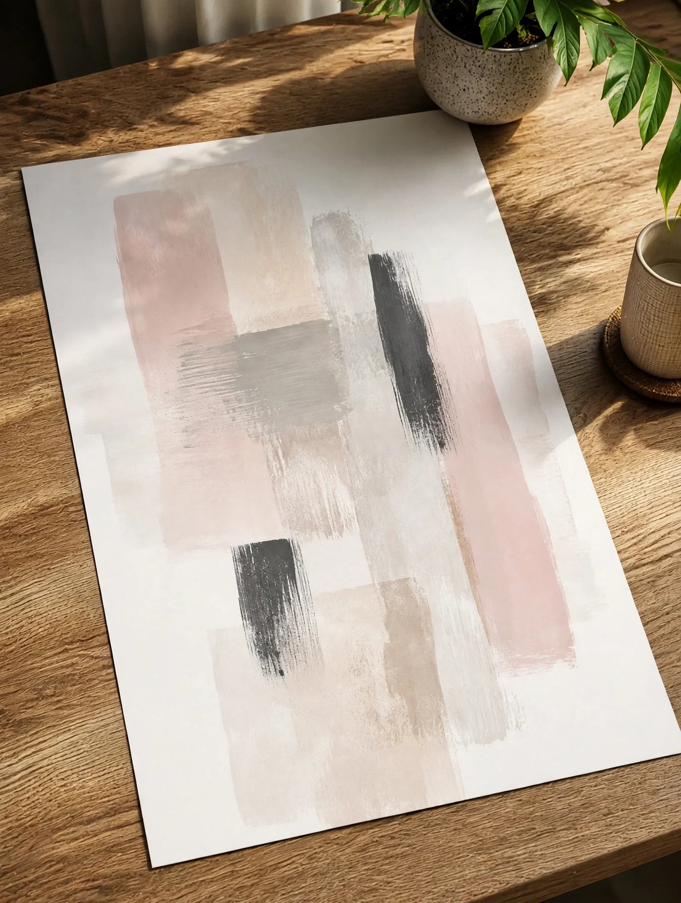 Unframed abstract art print with beige, gray, and black painted blocks on a wooden table