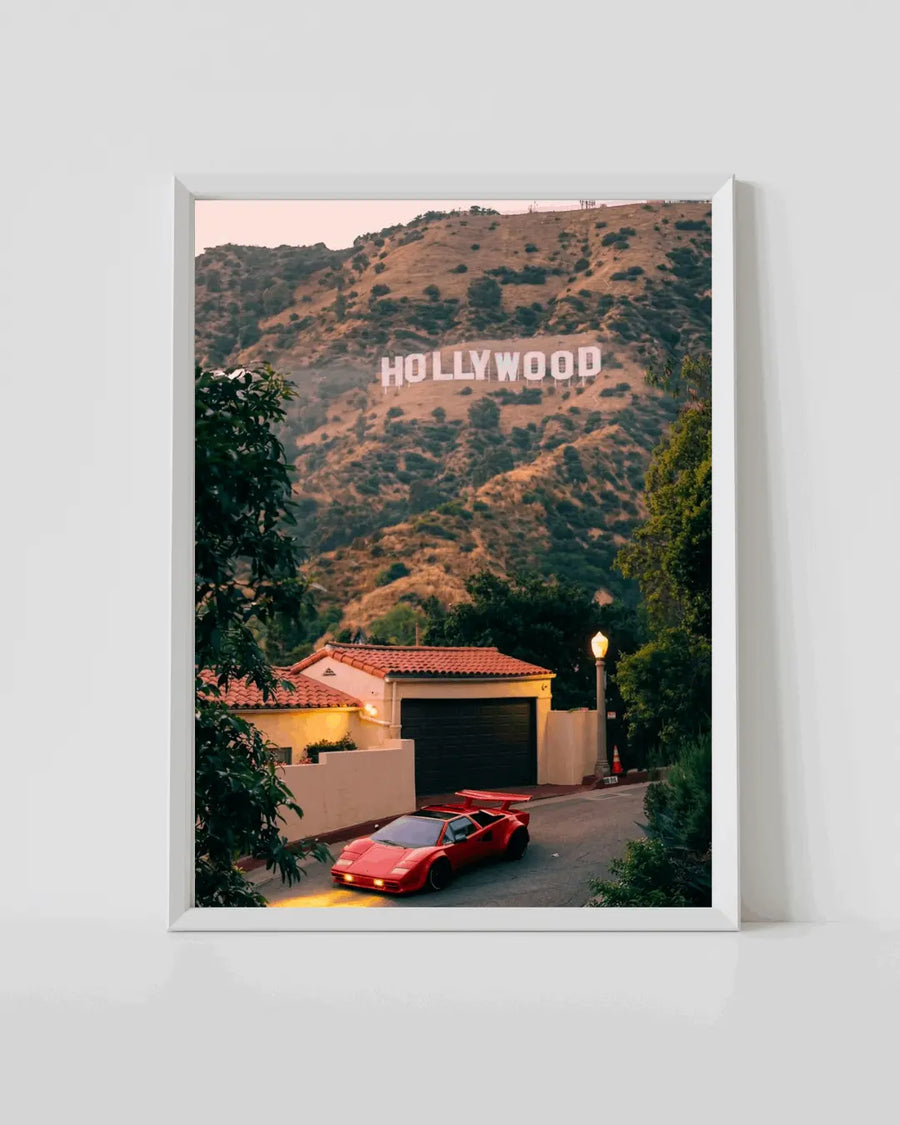 White-framed landscape poster with 'HOLLYWOOD' sign over hills and red car