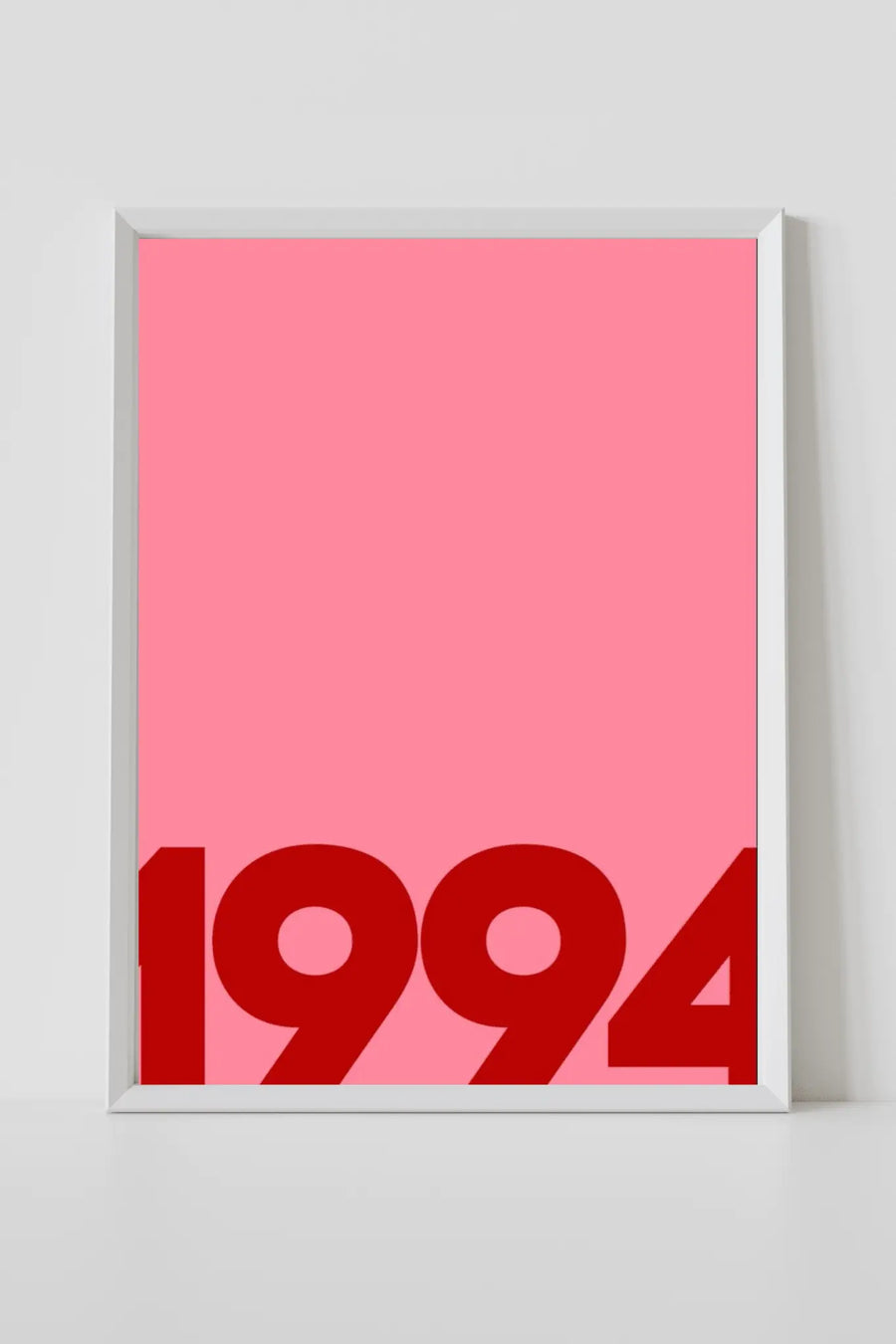 Póster de pared con marco blanco, fondo rosa y números “1994” en rojo en la parte inferior
