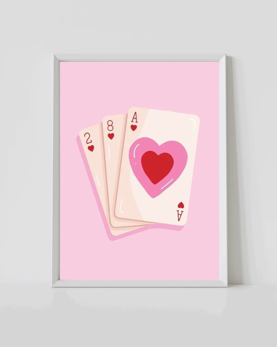 White-framed pink playing cards print with heart and card faces