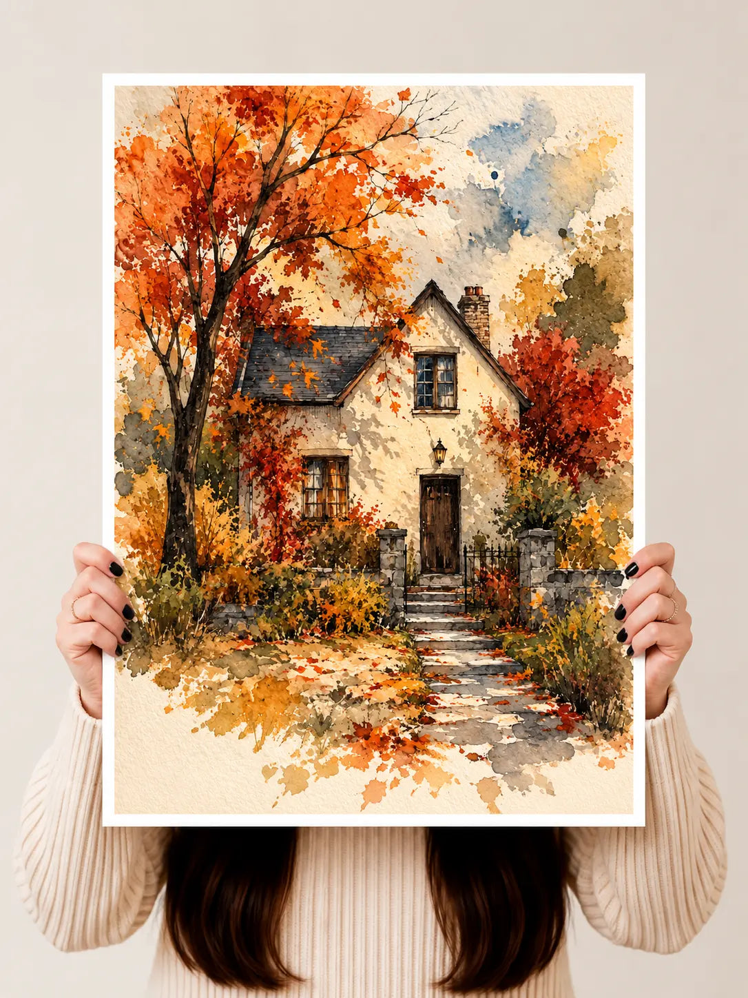 Watercolor cottage art print on white border, held by hands with autumn walkway
