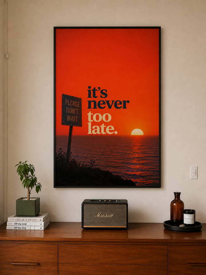 Black-framed motivational wall art with “it’s never too late” on an orange sunset background.
