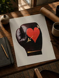 Boxing love print on white paper: black glove with red heart, laid on wooden desk
