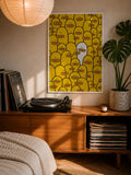 Framed yellow character-face graphic wall art with dark border.