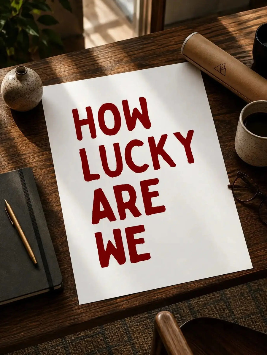 Quote print paper with red 'How lucky are we' text on wooden desk