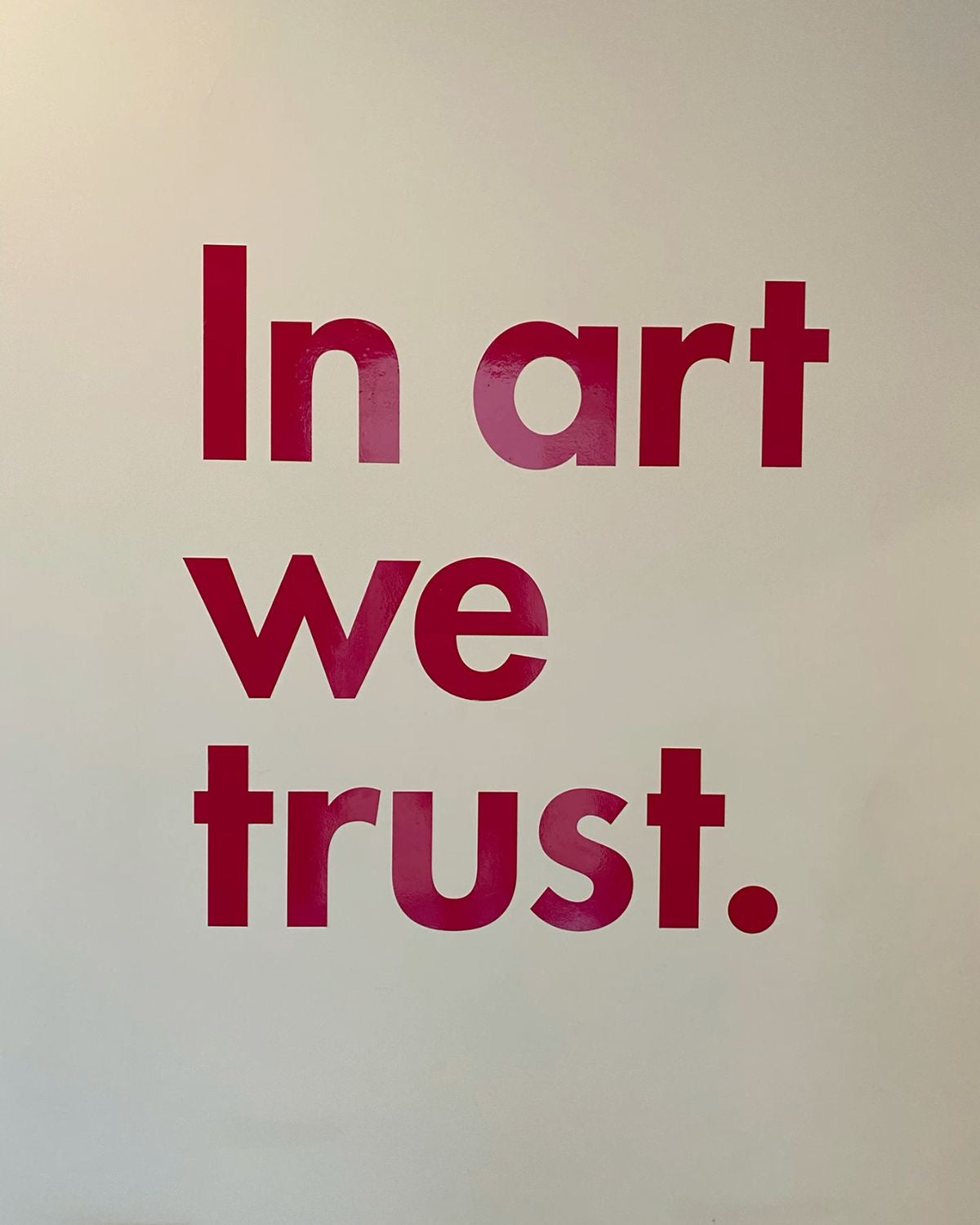 Typography wall print with bold red "In art we trust." text on white background