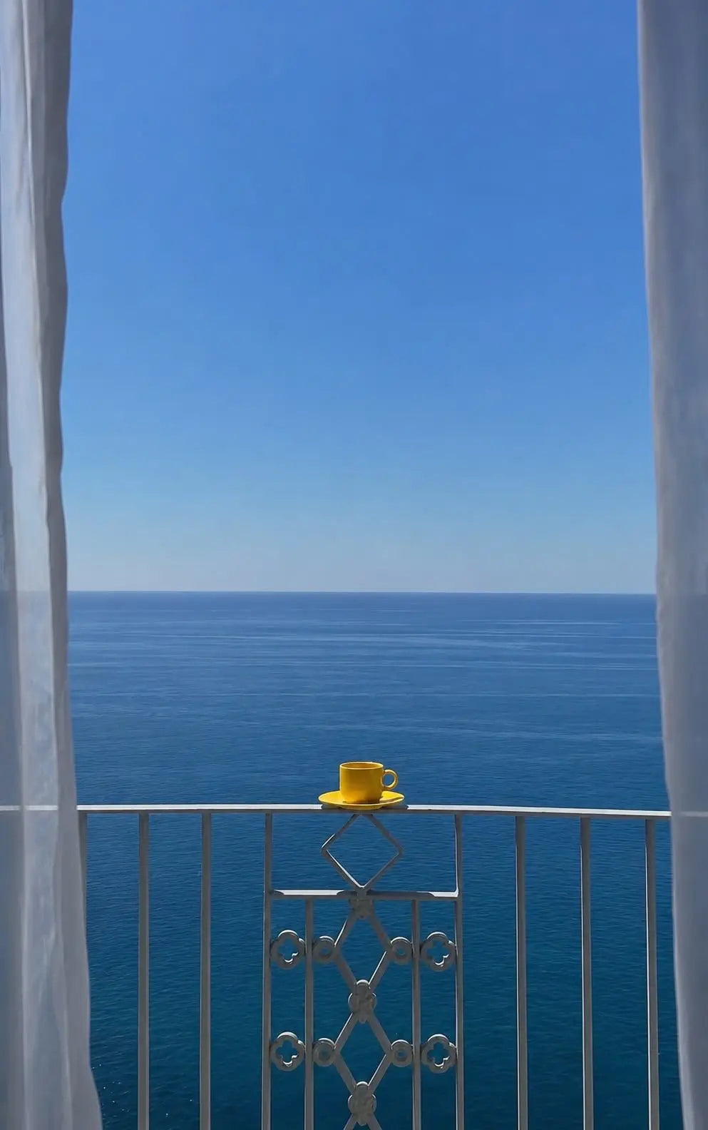 Sea view balcony print close-up of ocean and balcony railing with yellow tea cup