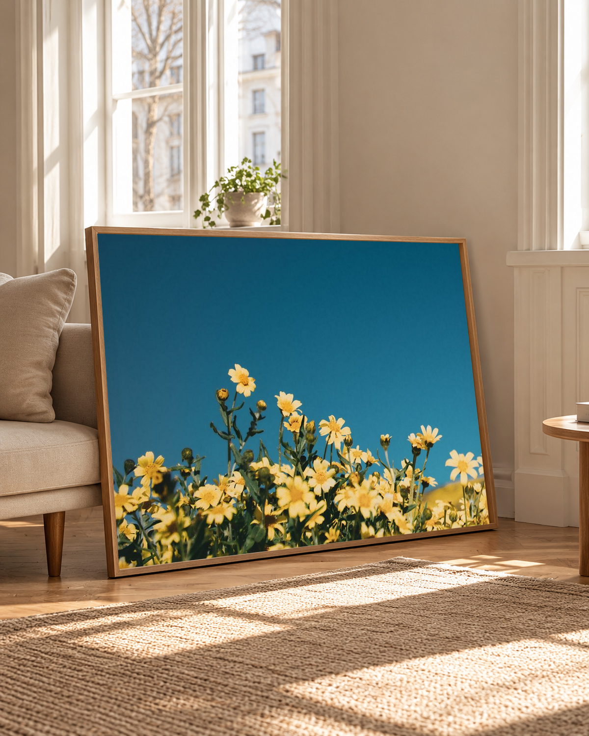 Yellow wildflower artwork leaning against a wall in a bright interior, surrounded by warm sunlight and natural wood flooring.
 Copy Alt Text