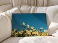 Blue and yellow floral print resting against soft white bedding, with delicate wildflowers bringing a colorful botanical accent to the bedroom.
 Copy Alt Text