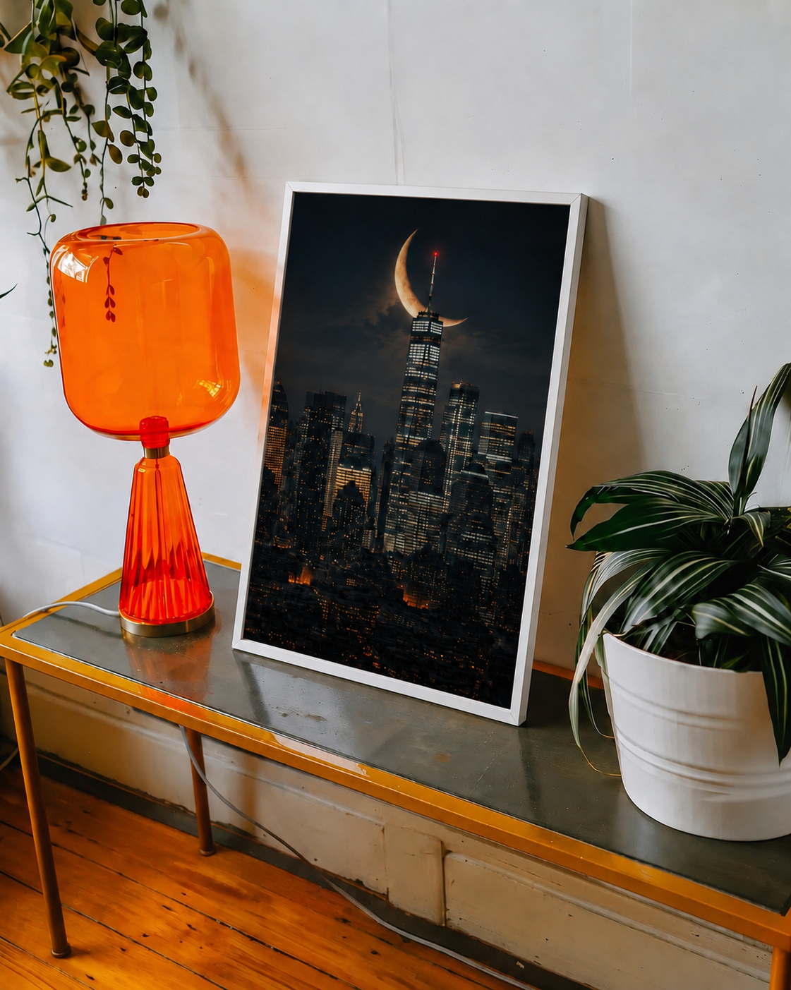 Framed city skyline art with crescent moon, white frame standing indoors