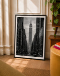 Black-framed black-and-white NYC skyline art print leaning near plants