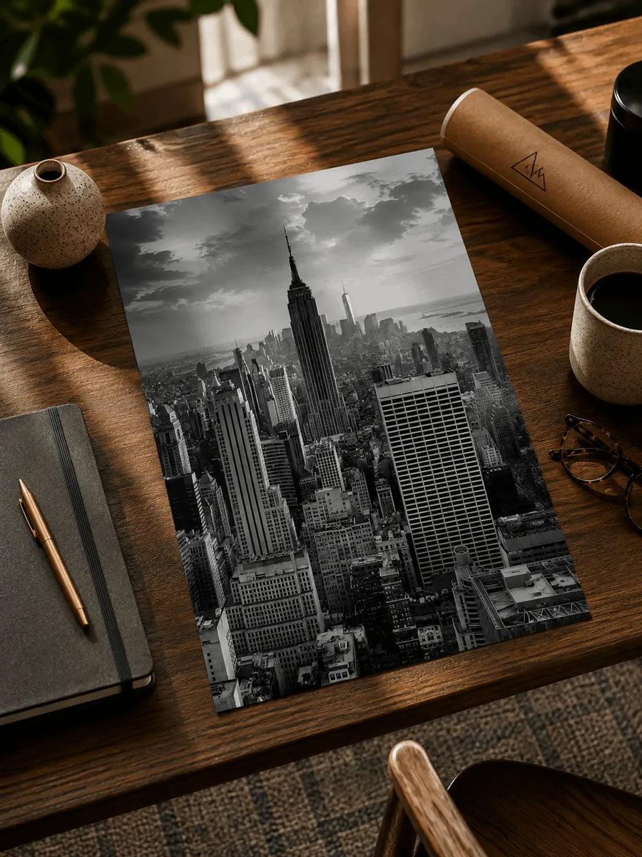 Vertical black-and-white New York City skyscraper poster on a wooden desk, unframed
