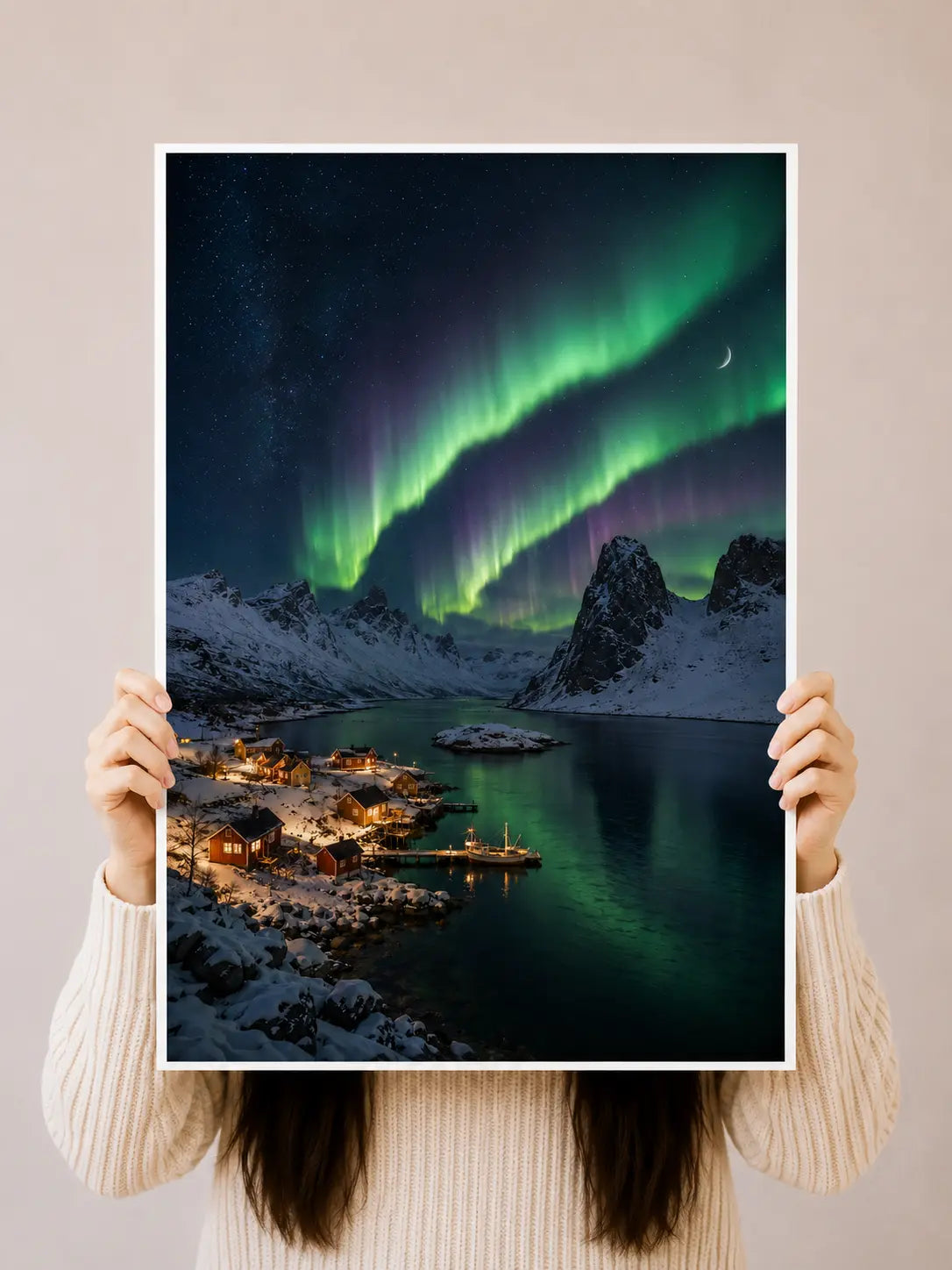 Northern Lights aurora art print held up, snowy harbor village with green aurora and crescent moon