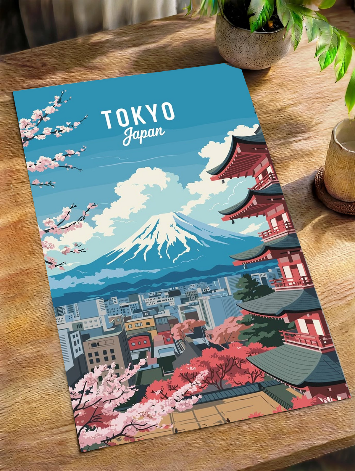 Wall art print on wooden table: blue Tokyo skyline, Mount Fuji, and cherry blossoms