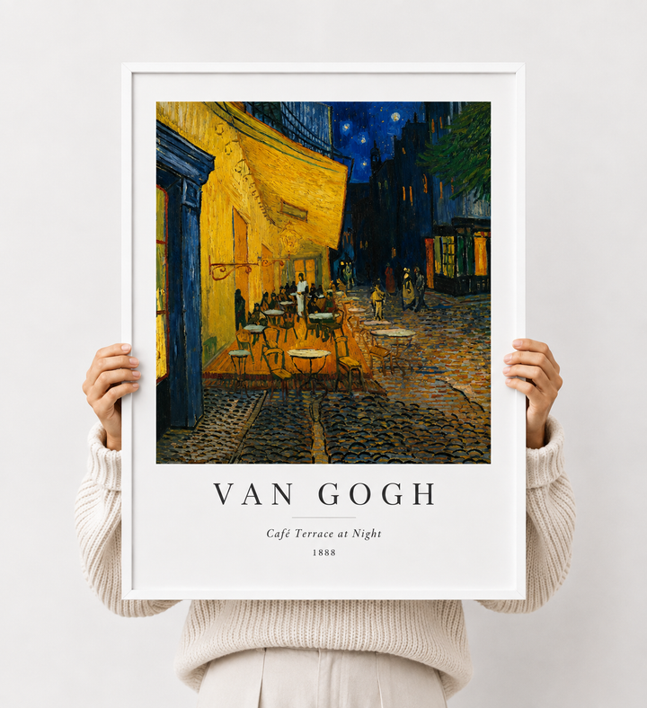 White-framed art print of cafe terrace at night with yellow facade and blue street