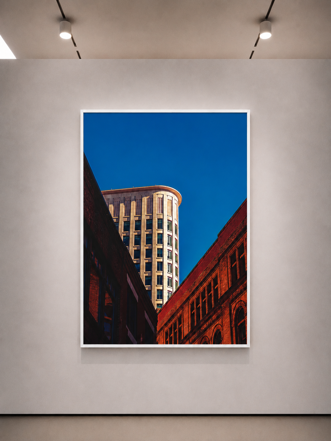 Poster verticale con bordo bianco che mostra un edificio alto e una strada in mattoni rossi sotto un cielo blu