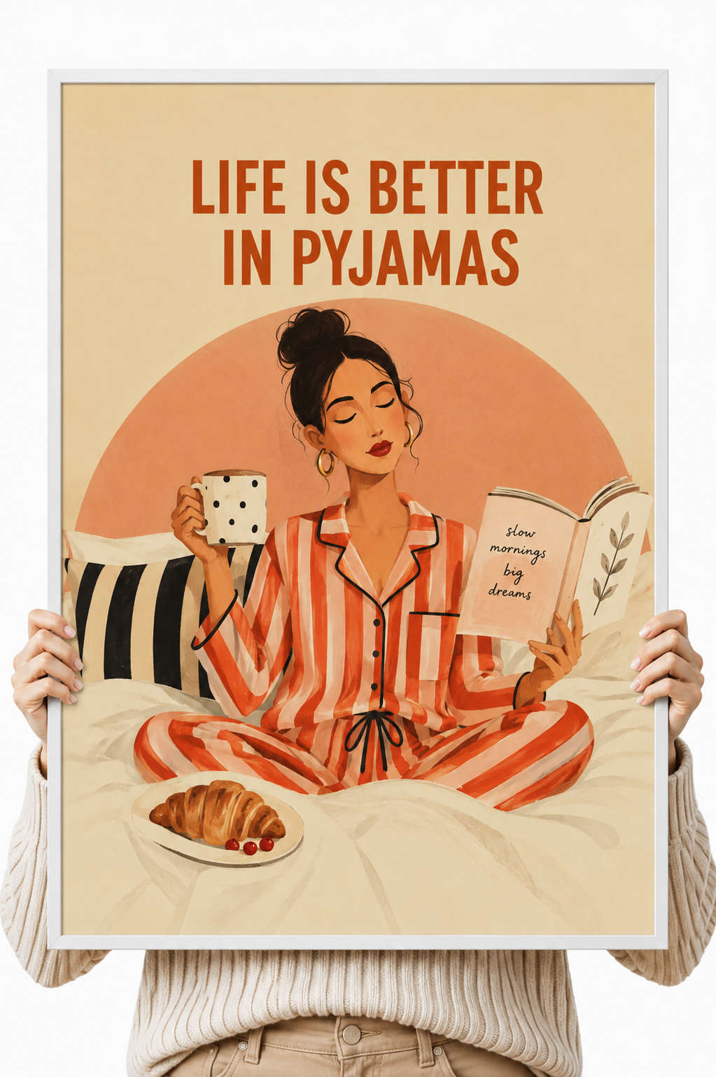 Wall art poster held by hands, woman in striped pajamas with mug and open book