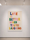 Bunter Typografiedruck mit „LIFE IS BETTER WHEN YOU’RE LAUGHING“ auf hellem Grund.