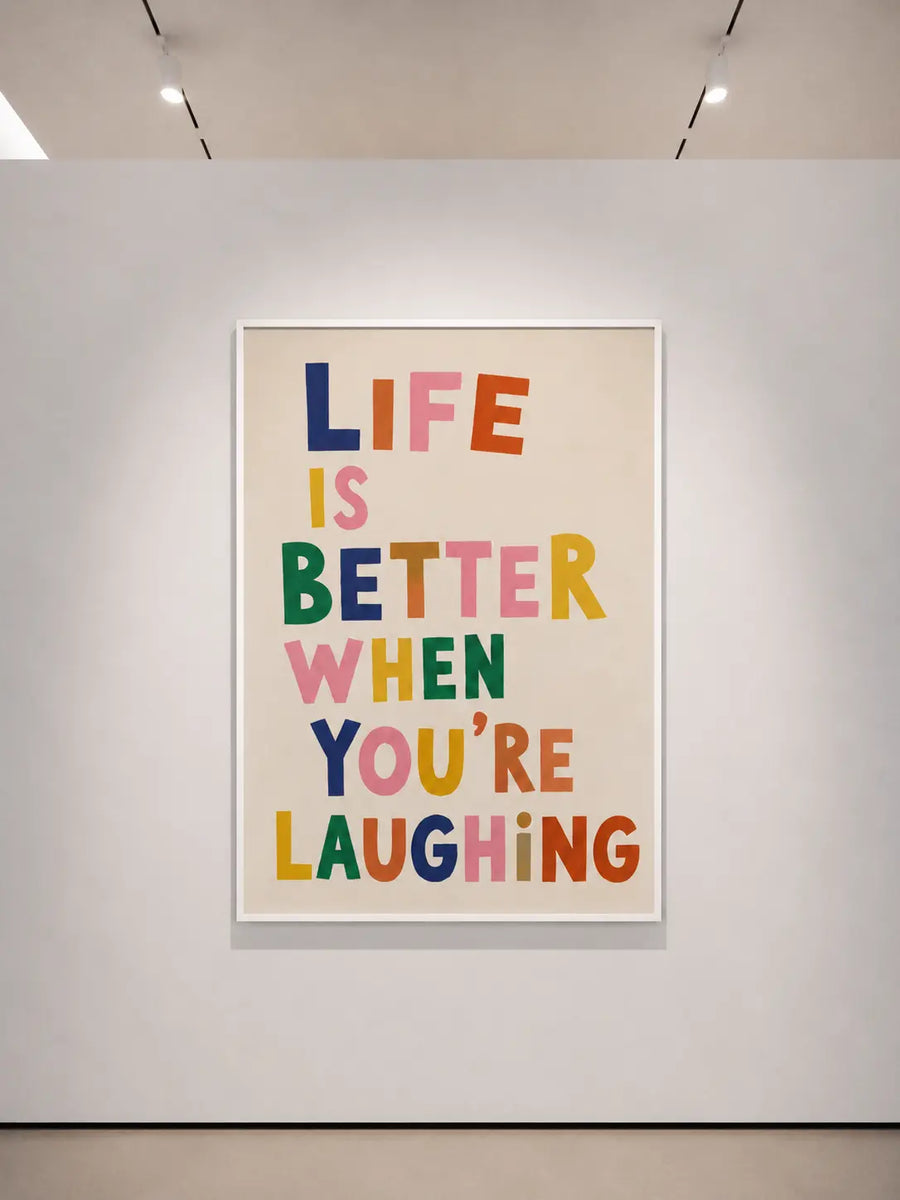 Quadratisches typografisches Wandposter im hellen Rahmen; Aufschrift: „DAS LEBEN IST BESSER, WENN DU LACHST“