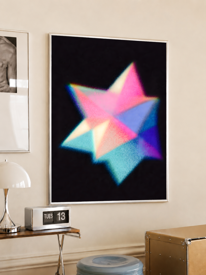 Overlapping pink cyan blue and purple geometric star shapes with grain and soft glow on black, styled in a light frame on a cream wall beside a white dome lamp and glass side table
