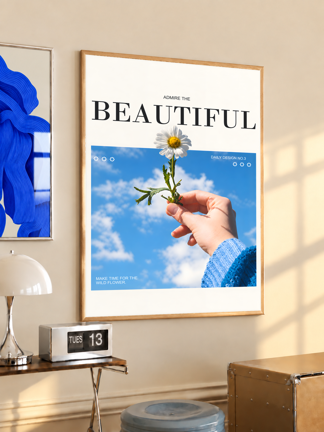 Hand holding a white daisy under blue sky with Admire the Beautiful lettering; oak framed print in a desk setting