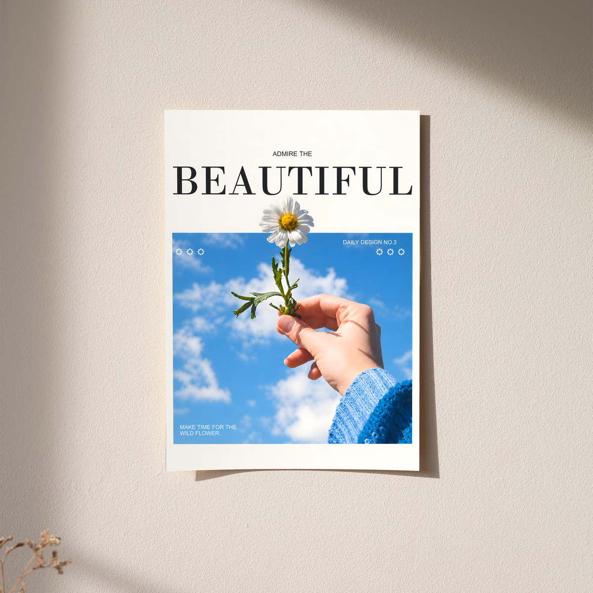 Hand holding a white daisy under blue sky with Admire the Beautiful lettering; unframed print on a wall