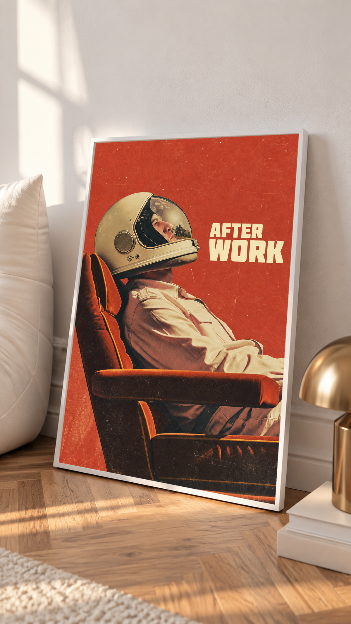 An astronaut reclining in an armchair against a burnt-orange ground in a white frame on a sunlit floor beside a white cabinet