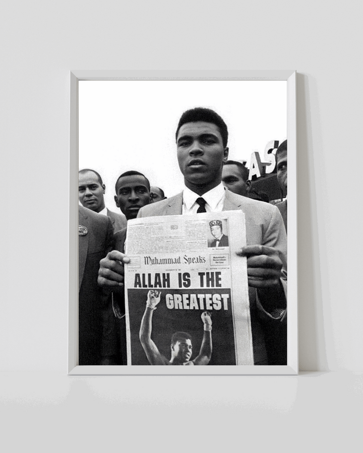 White-framed black-and-white poster of Muhammad Ali holding newspaper with 'ALLAH IS THE GREATEST'