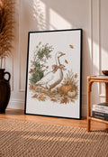 White goose with a rust pink bow among pumpkins and scattered autumn leaves in a black frame leaning on a sunlit wooden floor beside books and a rattan seat