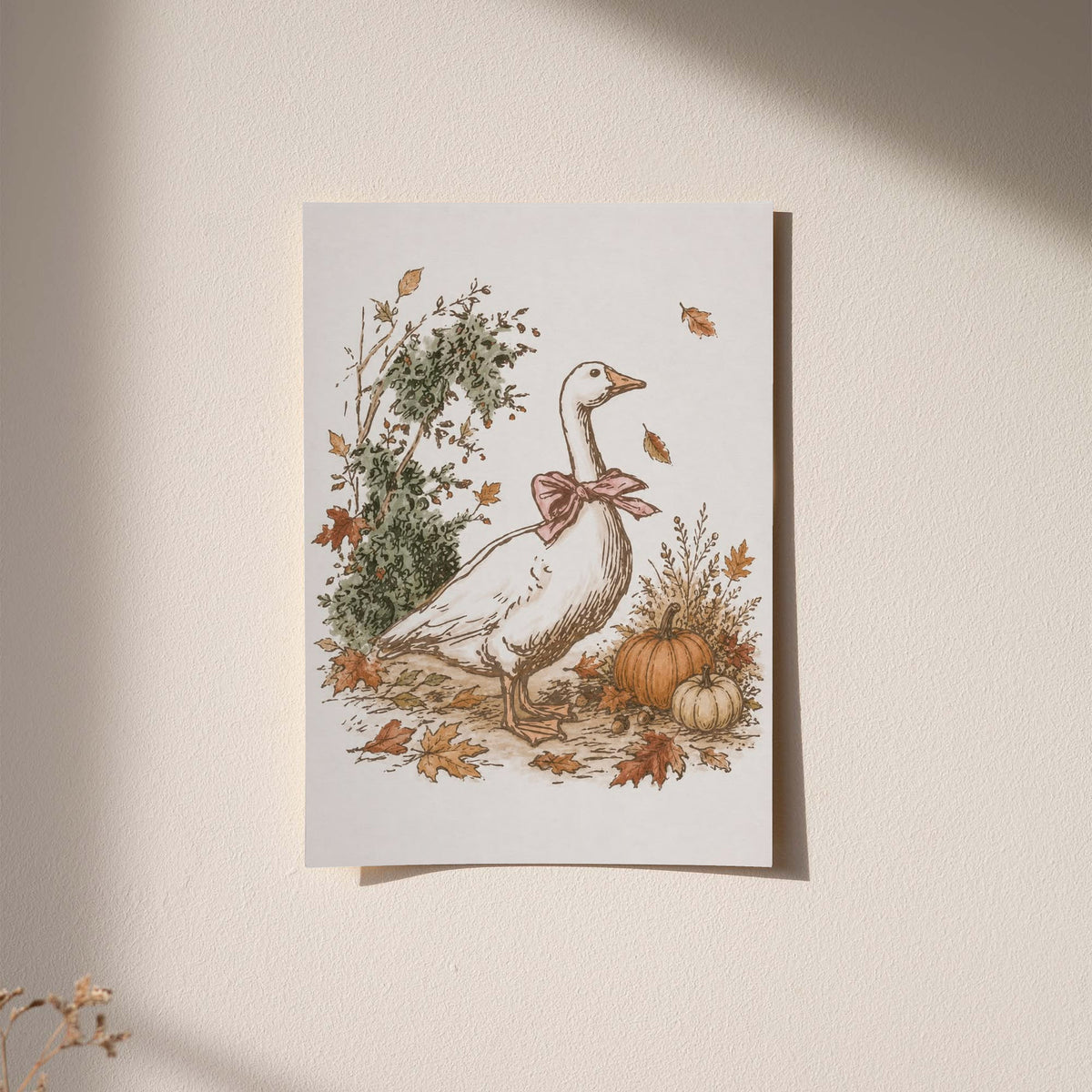 White goose with a rust pink bow among pumpkins and scattered autumn leaves as an unframed hanging paper print against a plaster wall
