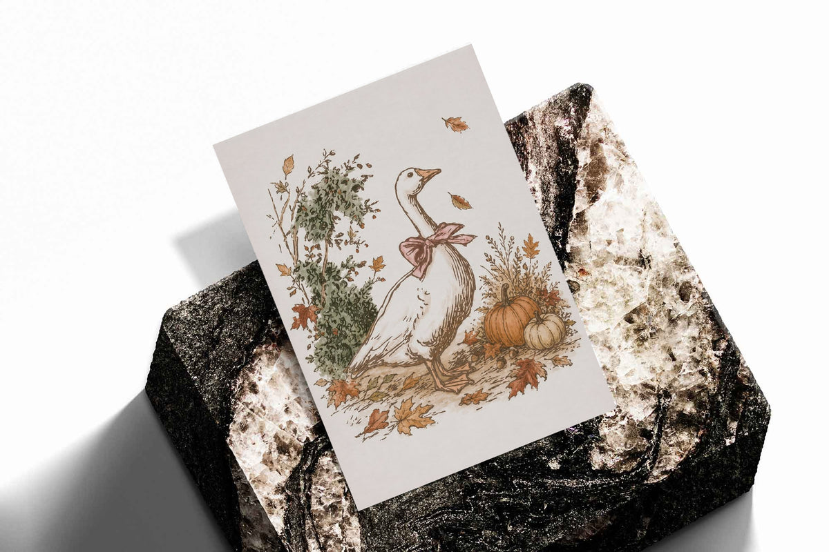 White goose with a rust pink bow among pumpkins and scattered autumn leaves as an unframed print standing on a stone plinth against white