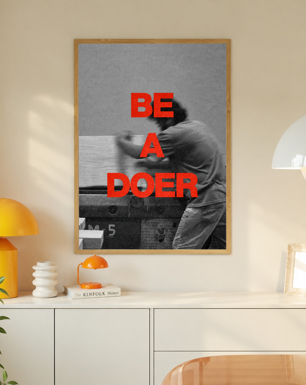 Framed motivational poster with red 'BE A DOER' text and black-and-white raised-arm photo