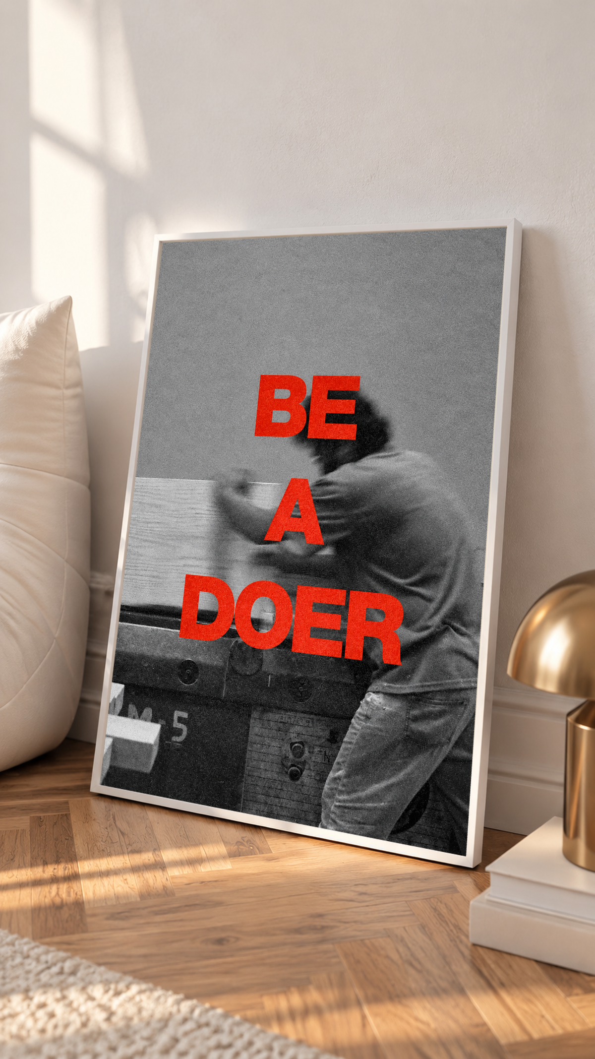 Red Be a Doer lettering over a motion-blurred monochrome figure in a white frame on a sunlit floor beside a white cabinet