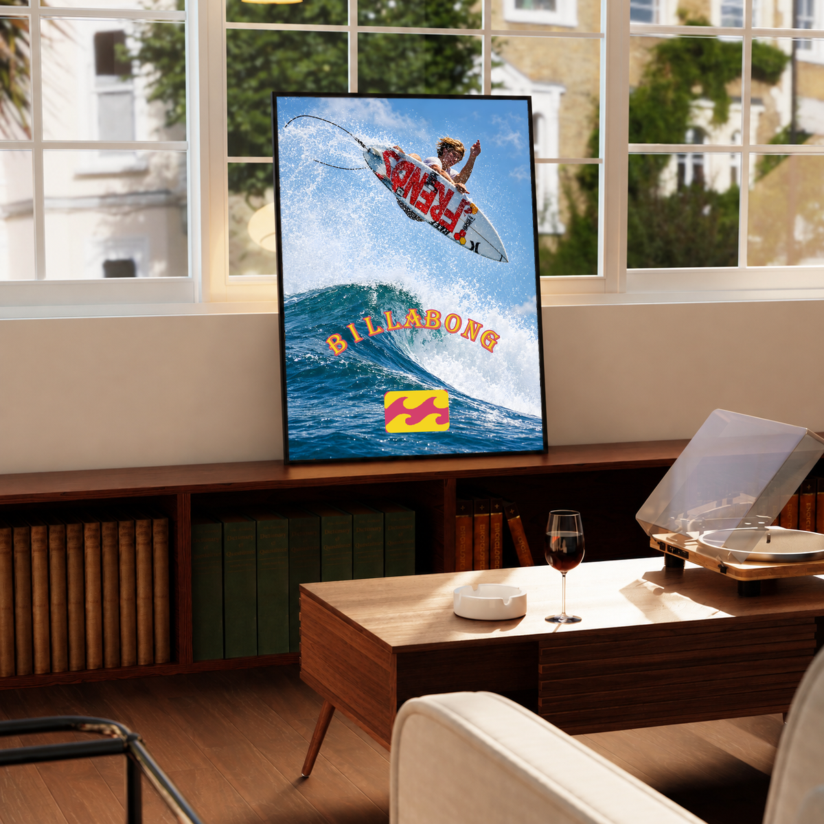 Airborne surfer above a blue wave with orange Billabong lettering; framed print beside a window