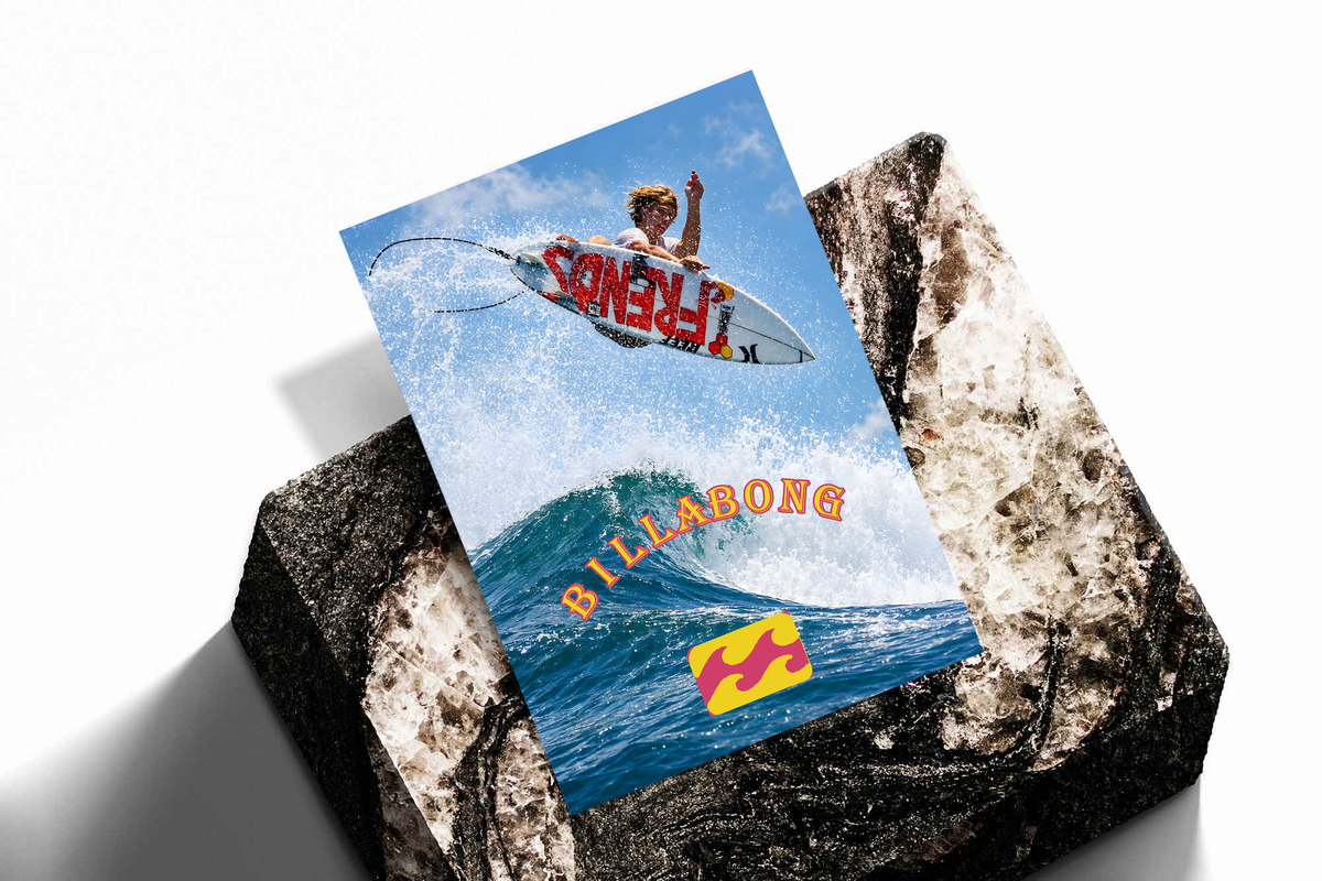 Airborne surfer above a blue wave with orange Billabong lettering; unframed print on a stone display