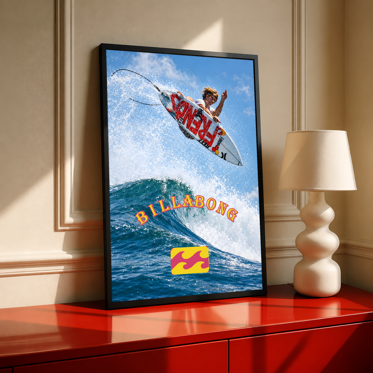 Airborne surfer above a blue wave with orange Billabong lettering; black framed print on a red cabinet