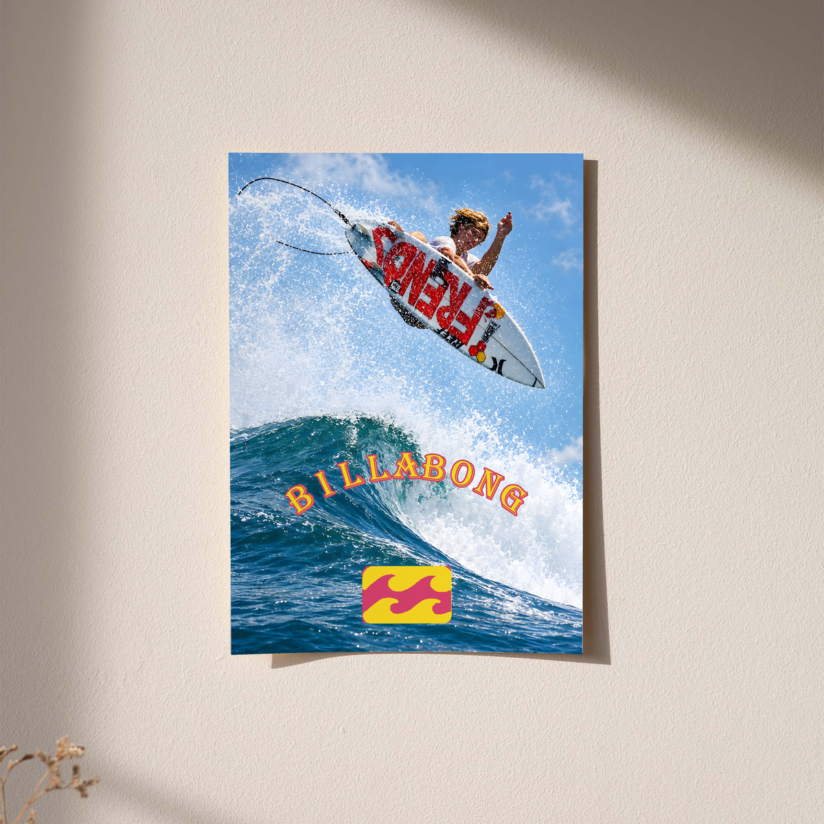 Airborne surfer above a blue wave with orange Billabong lettering; unframed print on a wall