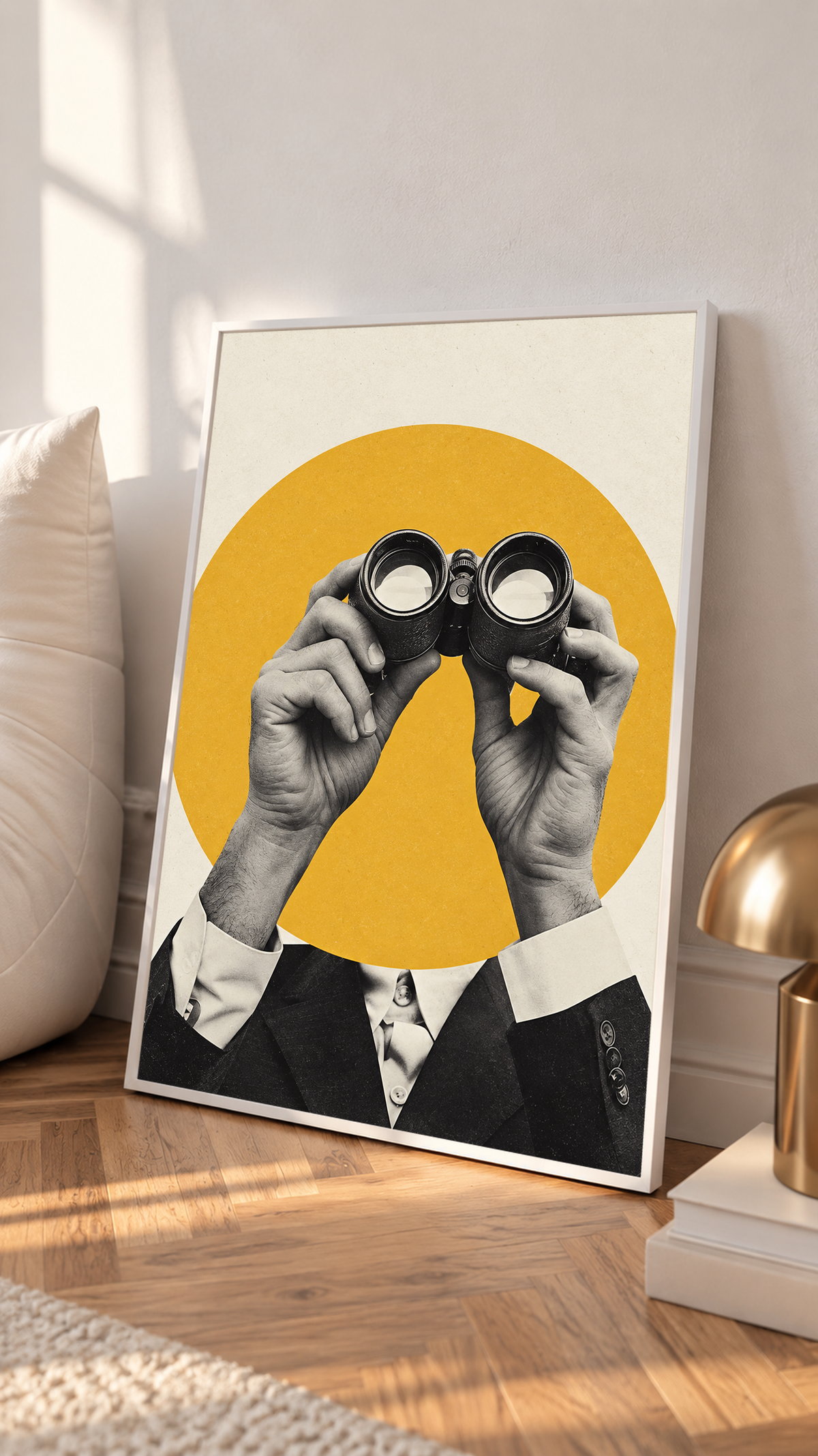 Monochrome hands holding binoculars before a mustard-yellow circle in a white frame on a sunlit floor beside a white cabinet