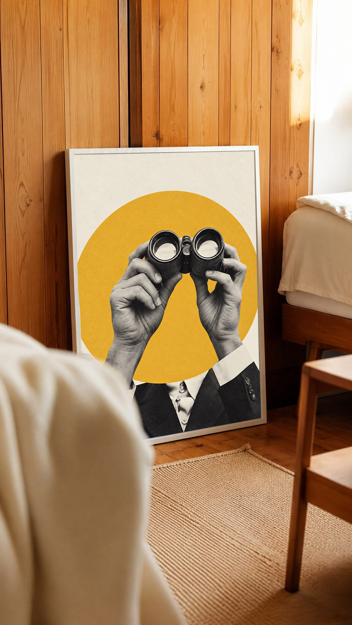 Monochrome hands holding binoculars before a mustard-yellow circle in a white frame leaning against warm wooden wall panels
