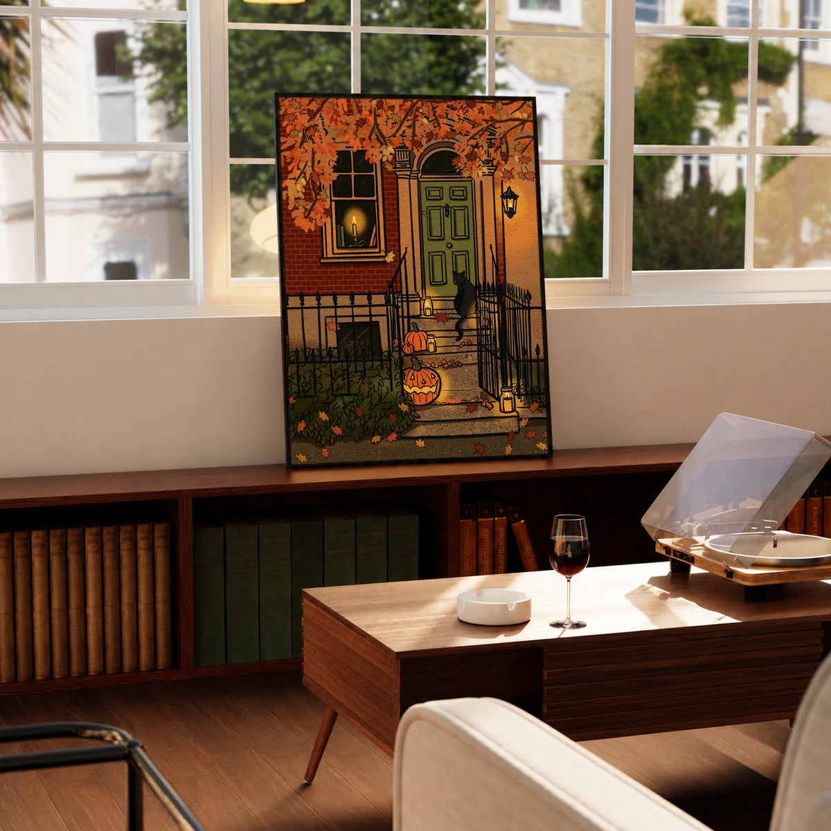 Halloween art print with green door and pumpkin yard scene, displayed on a wooden table