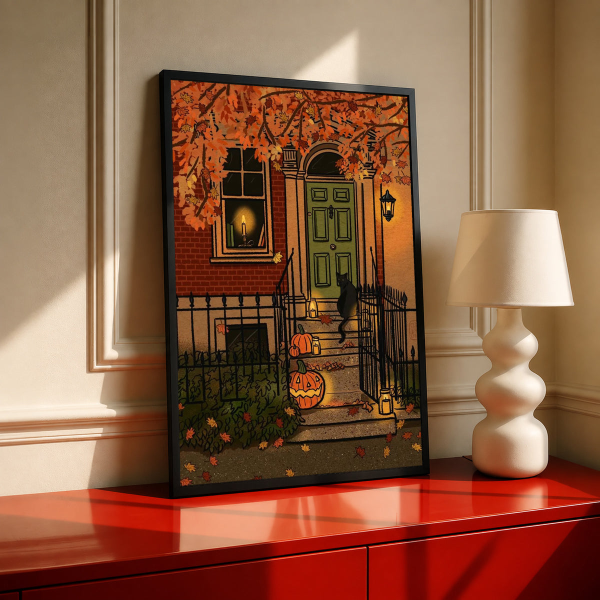 Black-framed Halloween art print showing green front door, pumpkins, and glowing lanterns