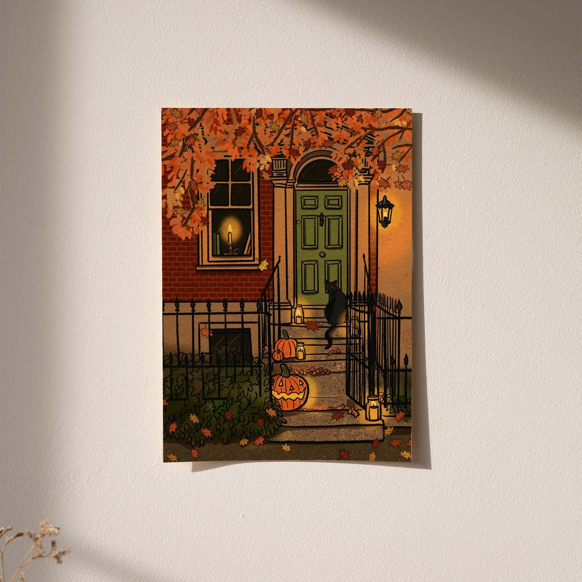Halloween art print in black frame on a wall, green door and carved pumpkin decorations