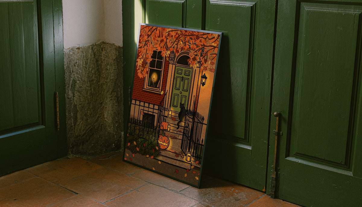 Halloween art print leaning against green doors, with jack-o'-lantern and gate artwork