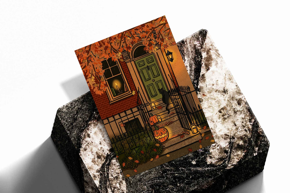 Halloween art print angled on textured black-and-white surface, green door and pumpkins