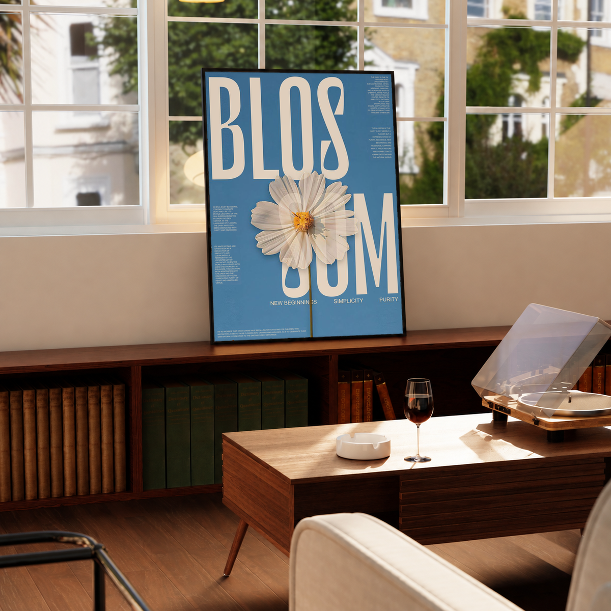 Framed blue poster on a table with cream lettering and a white daisy flower in front