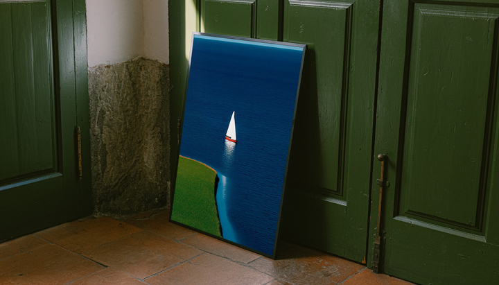 Blue Sailboat Shoreline Print shown as a canvas leaning beside green panels on a wooden floor.