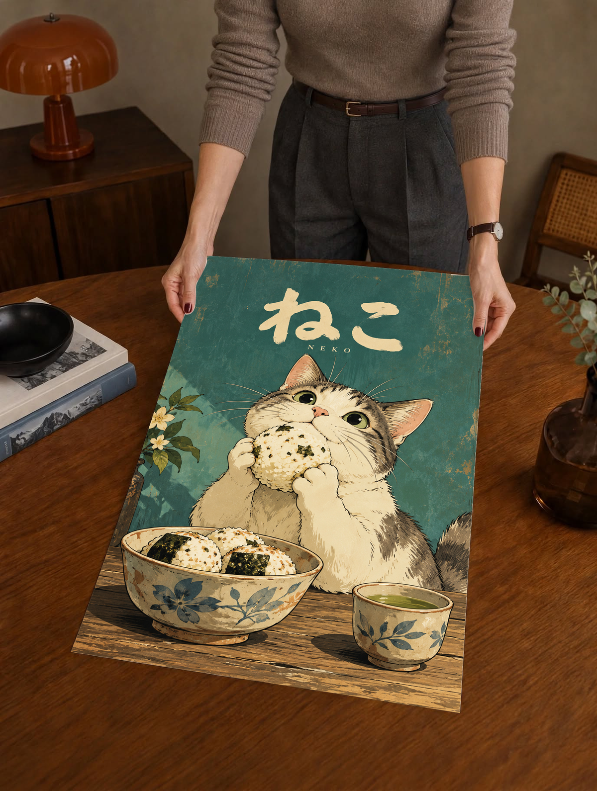 Cat poster framed on a table, Japanese “NEKO” letters above kitten holding onigiri.