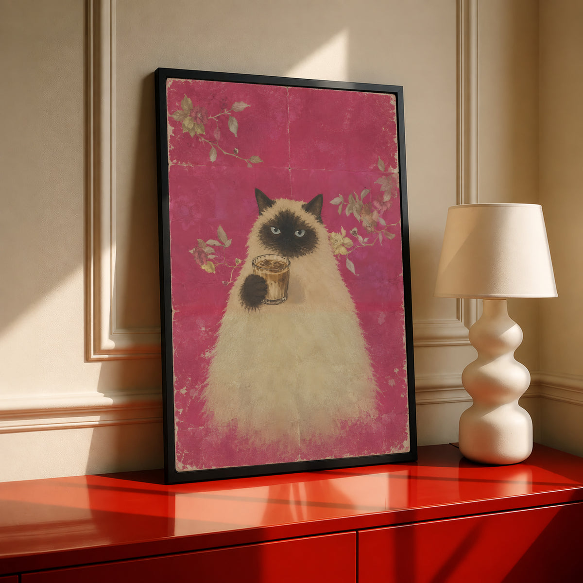 Black-framed portrait of a fluffy cat holding a cup of coffee on pink floral background